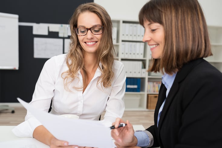 Close up Two Happy Young Businesswomen at the Office Talking About Business Report on Paper.